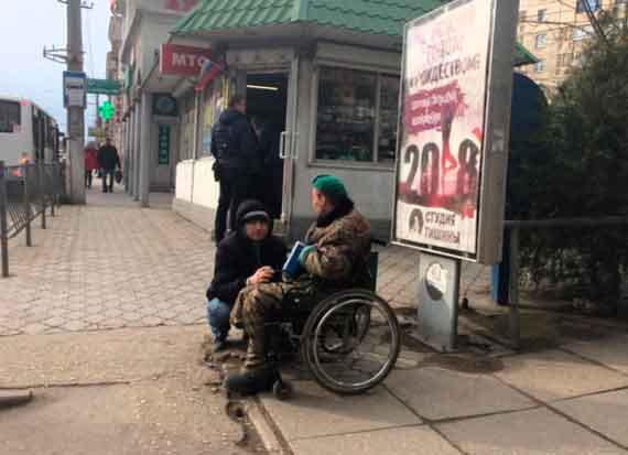 Колясочник в камуфляже просит подаяния на остановке