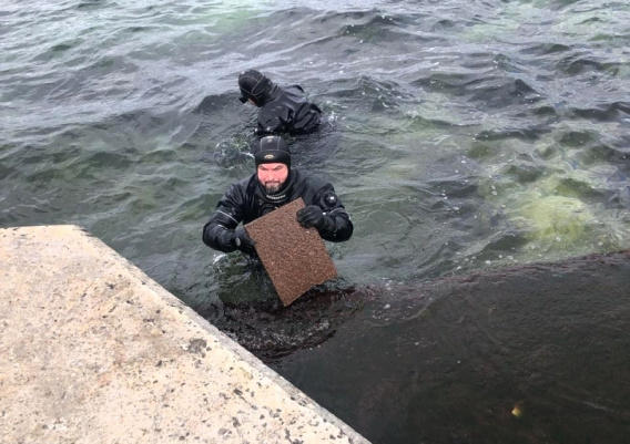 У Памятника затопленным кораблям группа водолазов пытается извлечь из воды смытую январским штормом гранитную плитку