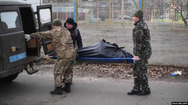 Украинские солдаты забирают тело гражданского мужчины с улицы в Харькове